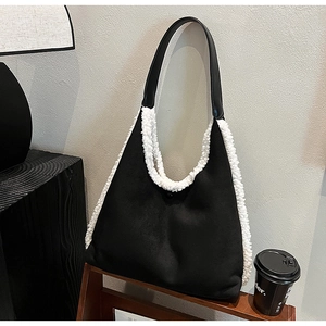 Close-up of contrast black suede tote bag with white plush trim on a wooden shelf