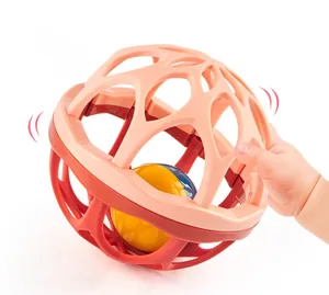 Close-up of baby grasping a soft mesh rattle ball with internal colorful ringing bell