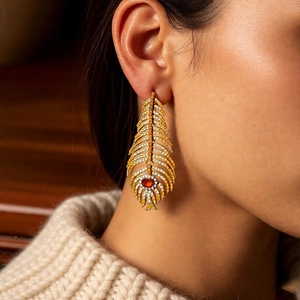 Close-up of vintage feather earrings with crystals and red gemstone on a model
