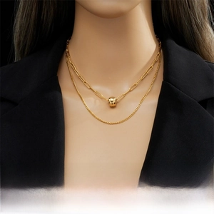 Detail of layered gold titanium necklace featuring a paperclip chain and faceted pendant