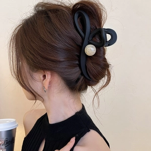 Detail of matte black claw clip with marble bead used for elegant updo hairstyle