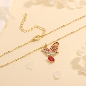 Close-up of golden hummingbird pendant with purple stones and a red oval gemstone detail