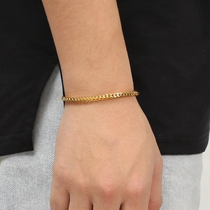 Detail of gold woven wheat chain bracelet on male wrist for daily minimalist styling