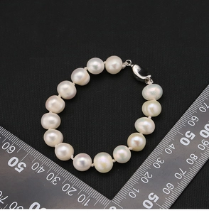 Detailed view of 12mm natural pearl bracelet with silver clasp on measurement scale