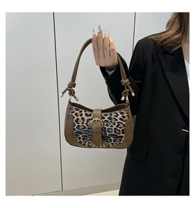 Detailed close-up of leopard print baguette bag with brown leather trim and gold buckle
