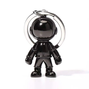 Detail of creative shiny black astronaut keychain with silver metal ring on white background