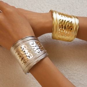 Detail of gold and silver hammered metal bangles with braided edges on female model
