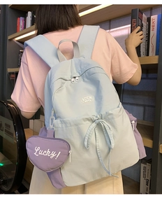 Close-up of light blue washed canvas backpack with purple heart charm in a library setting