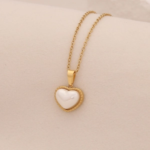 Detailed macro view of the 3D heart pendant and golden chain on a beige fabric