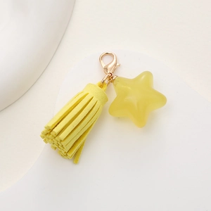 Detail of yellow star pendant keychain with soft suede tassel and golden clasp