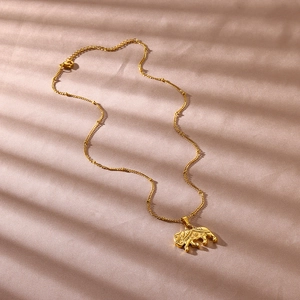 Detail shot of a golden elephant pendant necklace with bead accents on light purple silk fabric