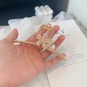 Elegant gold flower hair claw clip with rhinestones and pearl pendant on a white background