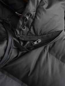 Detail shot of heavy-duty zipper and adjustable drawstring on black vest jacket