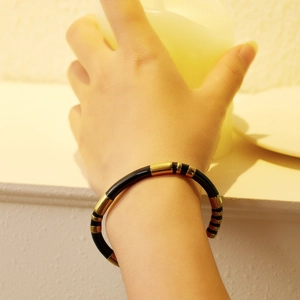 Macro shot of minimalist black enamel and gold stainless steel bamboo style bangle