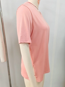 Dettaglio della maglietta rosa con scollo a V, spacco laterale e tessuto a maglia fine