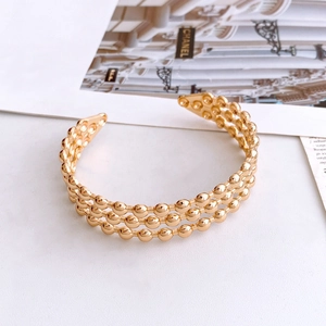 Elegant gold open cuff bracelet featuring a triple-row polished bead texture design