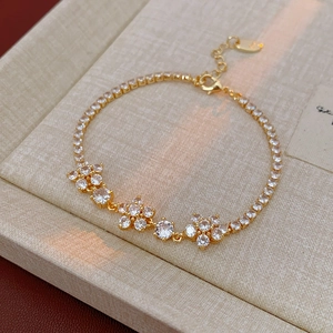 Detail of gold floral tennis bracelet featuring sparkling zircon flowers and a lobster clasp