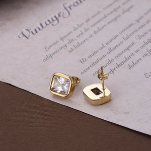 Elegant gold square stud earrings with clear cubic zirconia on vintage paper background