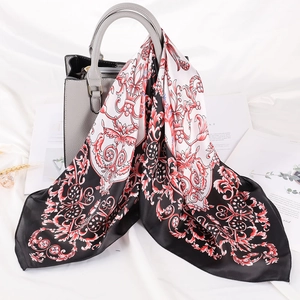 Dettaglio di un foulard a righe in seta elegantemente drappeggiato su borsa grigia