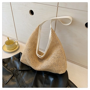 Close-up of woven straw tote bag texture with white leather strap in home setting