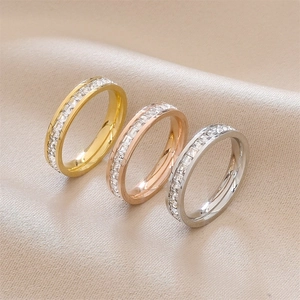 Three-color titanium steel eternity rings with zircon stones on champagne satin fabric