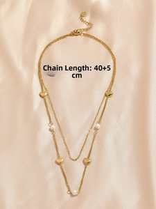 Detail of double-layered gold heart necklace with pearls on champagne silk fabric