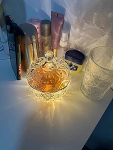 Macro shot of diamond pattern glass storage jar with amber scented candle and shadows
