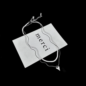 Close-up of a double-layered silver heart necklace with snake chain on white card background