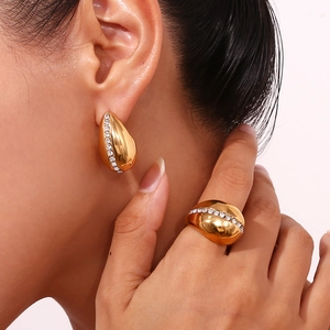 Close-up of gold waterdrop earrings and ring set with micro-pave crystals on model