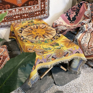 Detail of yellow Bohemian throw blanket with sun totem, floral patterns and fringed edges