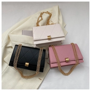 Close-up of quilted chain bags in white, black and pink with golden metal buckles