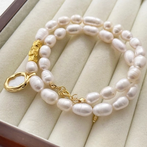 Baroque pearl necklace with 14k gold shell pendant and smiley face beads on tray