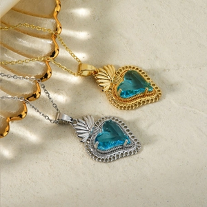 Detailed macro view of heart pendant necklaces with blue gemstones on sand background