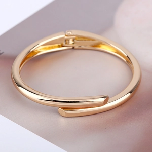 Detail view of a minimalist gold hinge bangle showing the polished cylindrical overlap