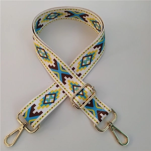 Close-up of geometric ethnic pattern bag strap with gold metal hooks on white background