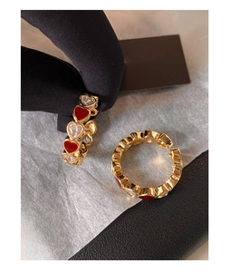 Close-up of gold plated heart ring with red enamel and sparkling zircon gemstones