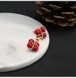 Detail of red bead cluster earrings in flower shape on white marble tray