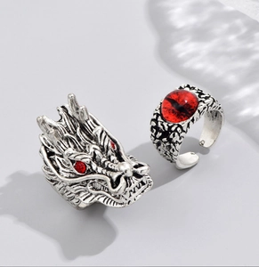 Macro detail of gothic dragon head ring and red evil eye ring set in vintage silver