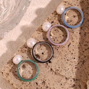 Detail of colorful enamel pearl rings in blue, purple, black and green on stone base
