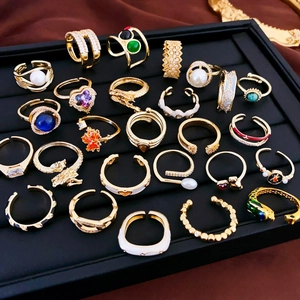 Detailed macro view of gold-plated rings with zircon and pearls on black velvet tray