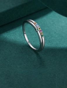 Macro shot of silver ring with colorful gemstones on a textured green background