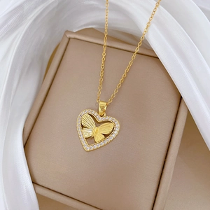 Detailed close-up of a gold heart pendant with a butterfly and sparkling crystals