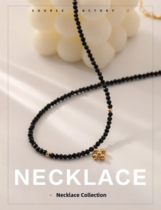 Close-up of black faceted beaded necklace with a golden floral pendant and metal spacers