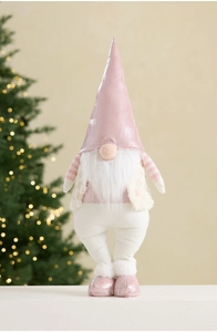 Pink and white Christmas gnome decoration with warm glowing tree in the background