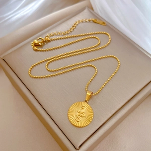 Macro shot of gold-plated snake pendant with sunburst texture on a bead chain necklace