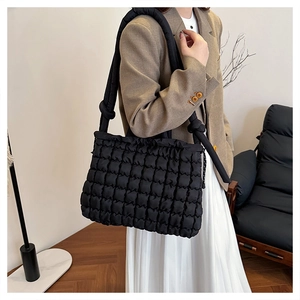 Detail of black quilted shoulder bag with cloud texture and adjustable knotted strap