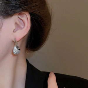 Détail de boucles d'oreilles argentées avec zircons pavés sur un mannequin femme