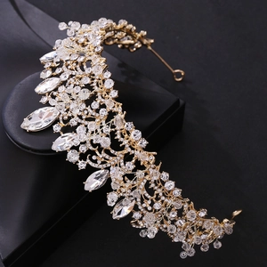 Detail of handmade gold bridal crown with shimmering crystals and leaf design
