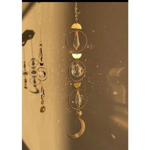 Golden suncatcher crystal with moon and droplets casting rainbow light on walls
