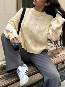 Outdoor street style view of beige cable knit sweater with chunky round neck design